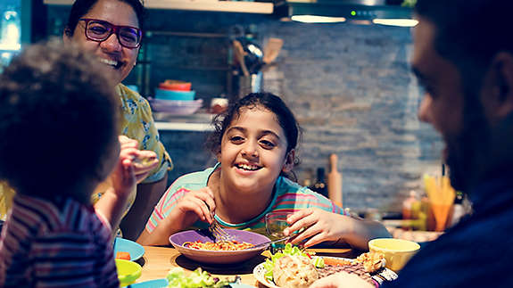 Family eats and laughs around kitchen table