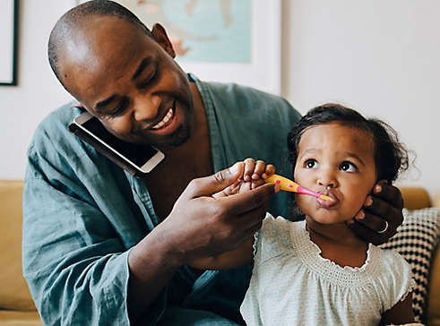 Dad brushing dauther's teeth