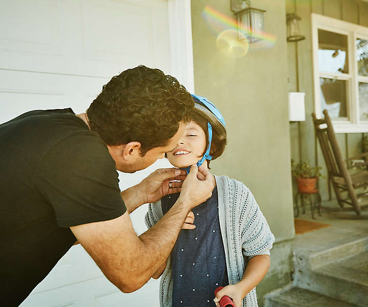 Father putting a bike helmet on his child.