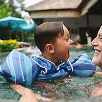 Older gentleman plays with grandchild in the pool