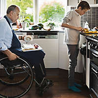 Middle-aged gentleman and son cooking together in kitchen