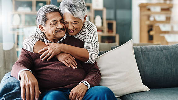 A mature couple hugging each other on the couch