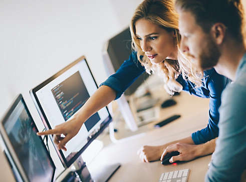 Two people checking charts on a computer