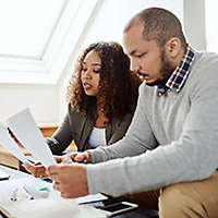 Two people sitting on a couch reviewing paperwork