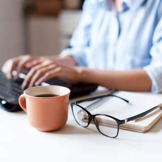 A woman sitting at a desk with a laptop, focused and working intently.