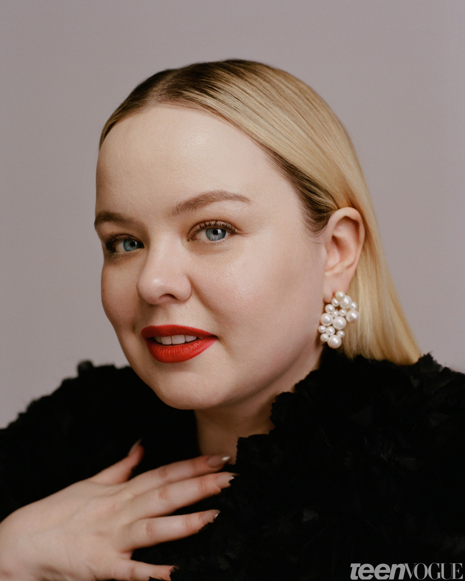 Nicola Coughlan in red lip with pearls and hand draped on her chest