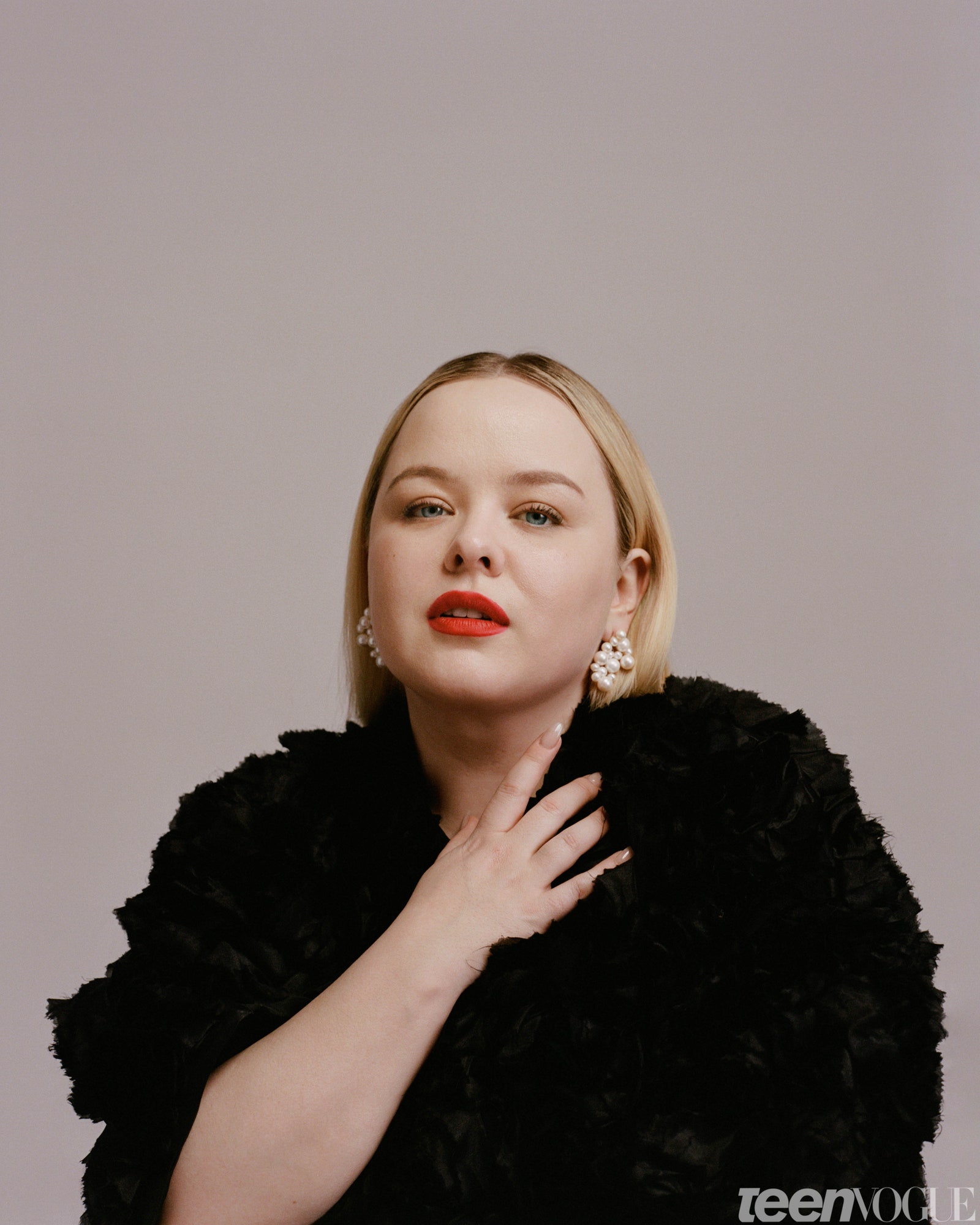 Nicola Coughlan in red lip with pearls and hand draped on her chest