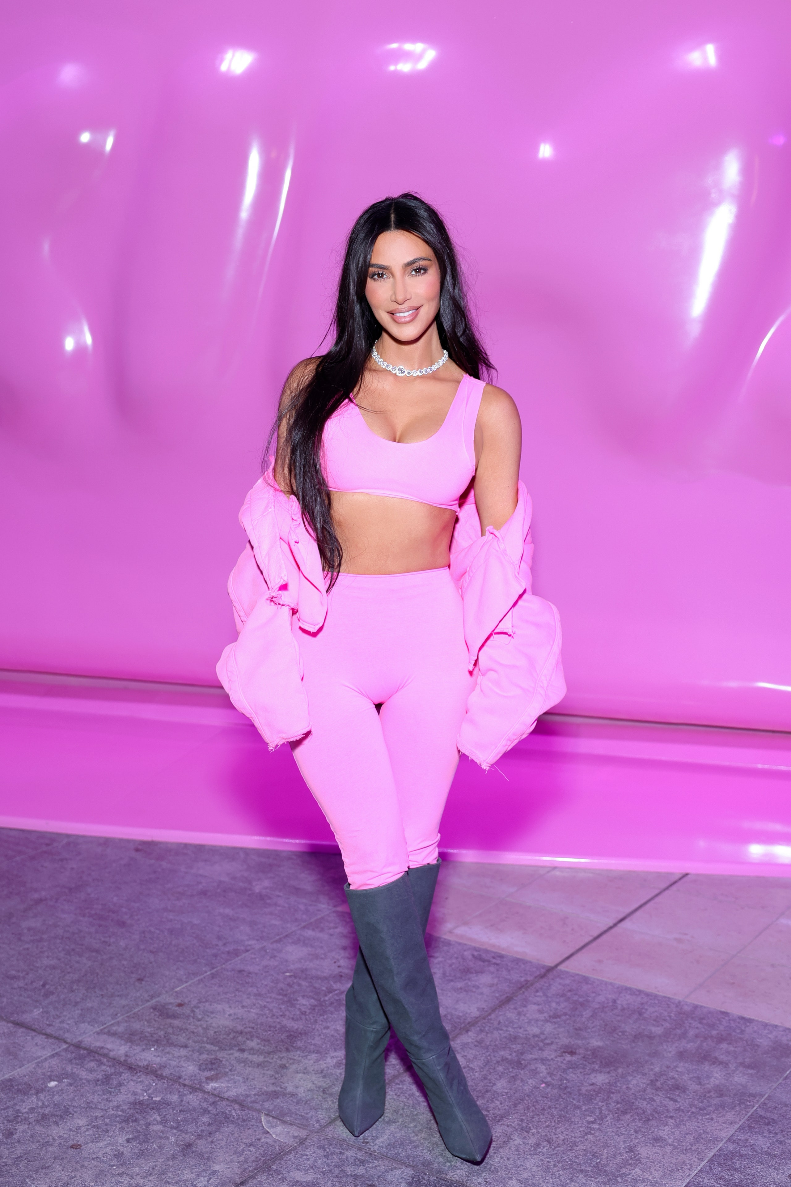 Kim Kardashian wears a pink sports bra leggings and gray kneehigh boots.