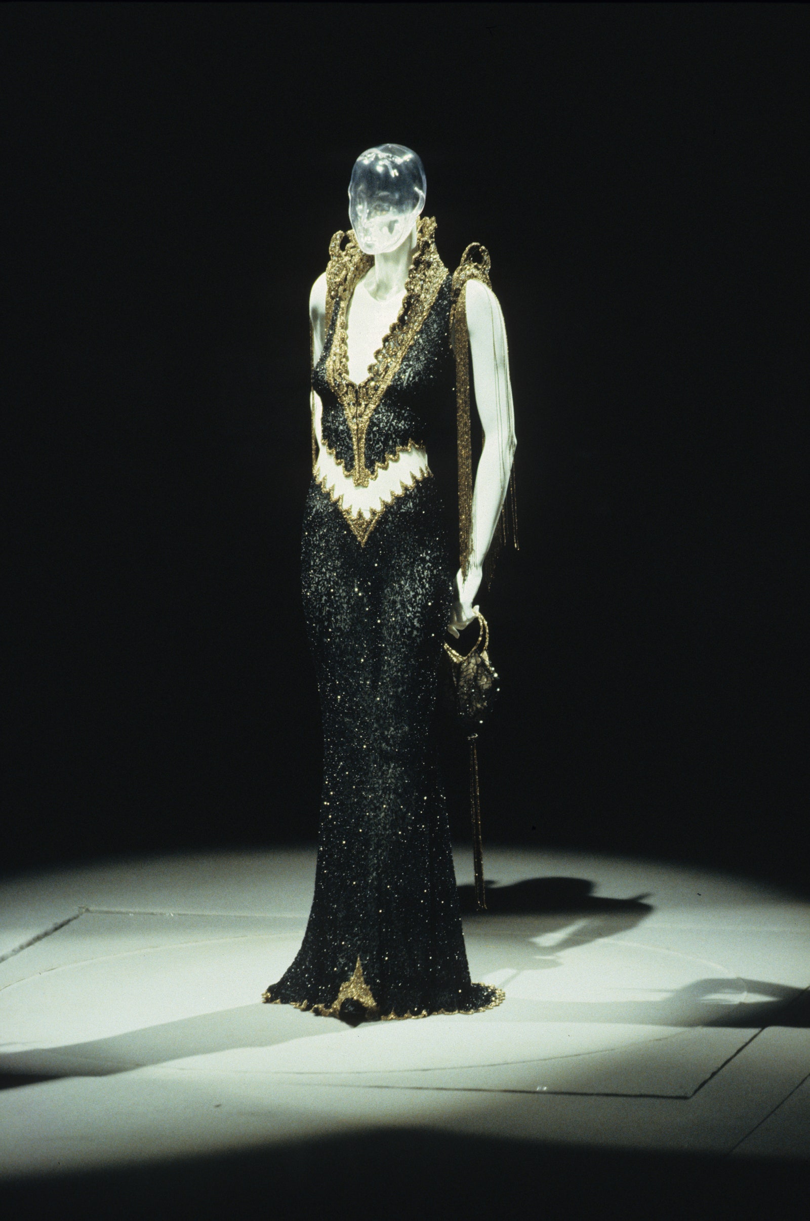 Floorlength sleeveless beaded black gown with cutout waist gold trim and stand collar in the Givenchy FallWinter 1999...