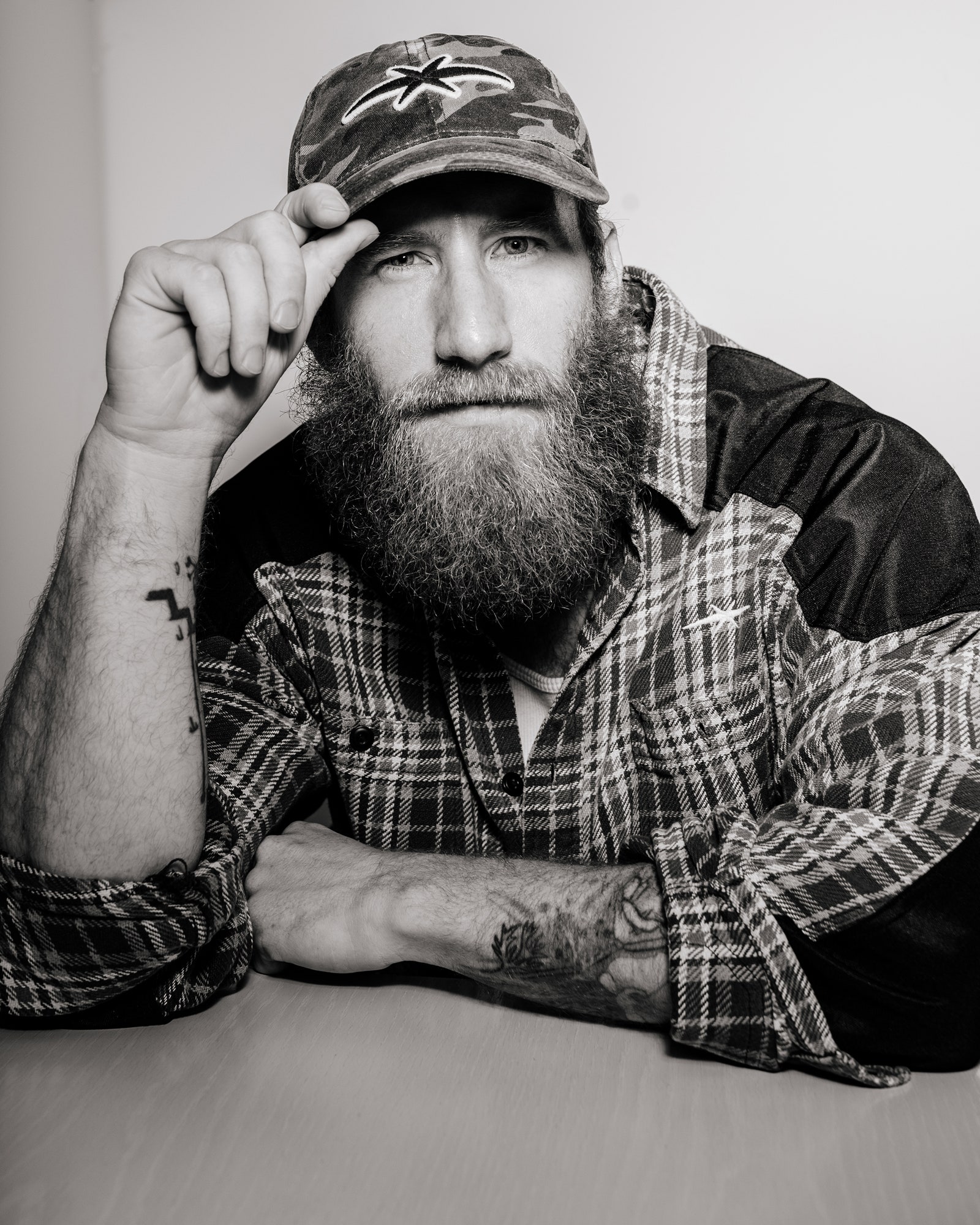 Image may contain Beard Face Head Person Photography Portrait Adult Skin Tattoo Baseball Cap Cap and Clothing