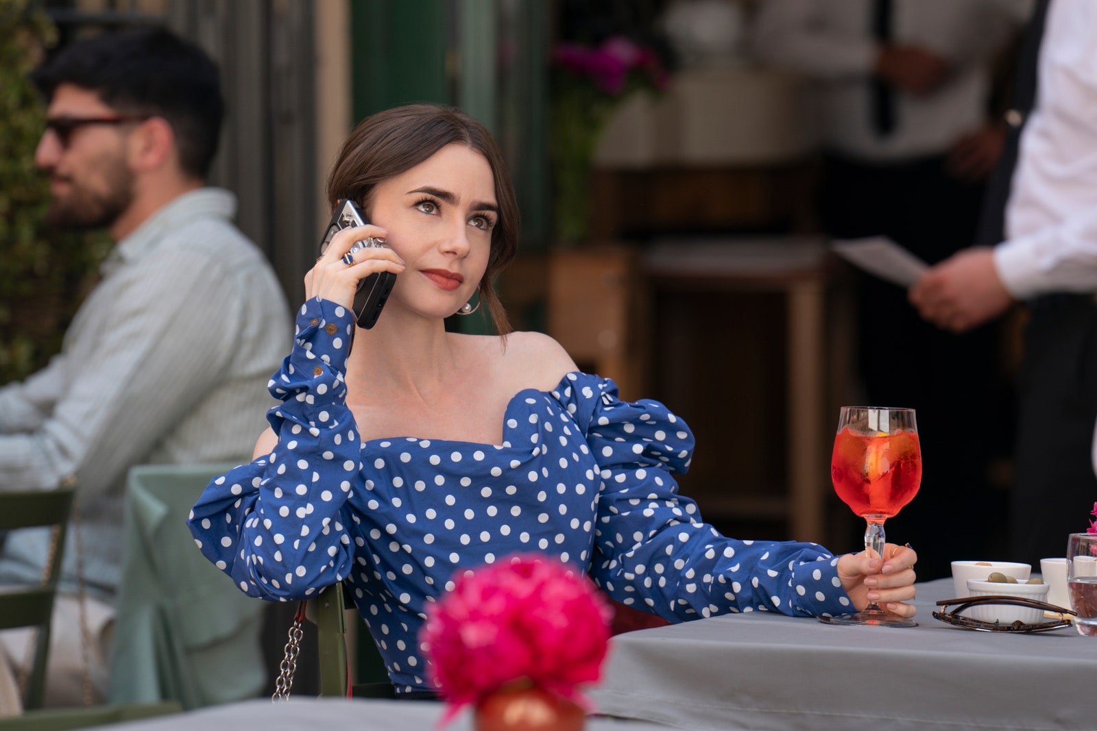 Image may contain Lily Collins Adult Person Chair Furniture Electronics Mobile Phone Phone Cup and Accessories