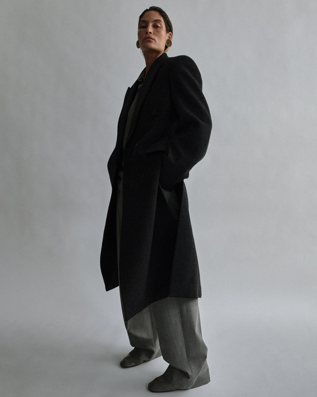 Mans coat in black wool cashmere. Uprightcollar shirt in bitter brown cotton poplin. Trousers and shoes from A2 edit...