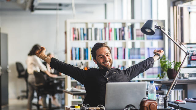 Businessman sitting with arms outstretched at desk in office 