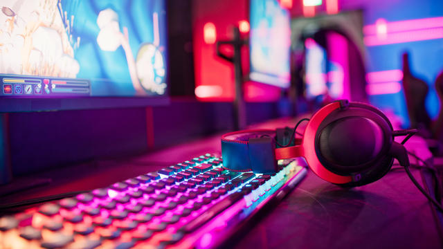 Pro gamer team computer setup at video game eSport championship with neon keyboard. Video game on monitor screen 