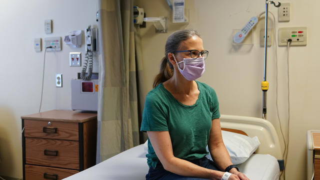 Female patient sitting on bed in hospital ward 