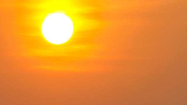 man drinking water with the sun over him 