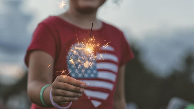 midsection of girl holding lit sparkler 