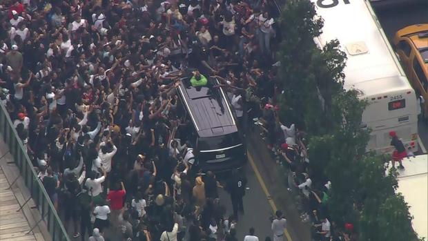 An aerial view of hundreds of people swarming an SUV as it tries to leave the Union Square area. A passenger looks out the moon roof. 