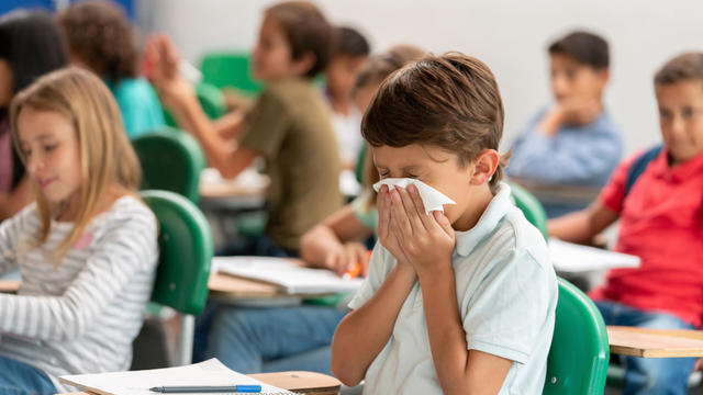 Sick boy at the school blowing his nose in class 