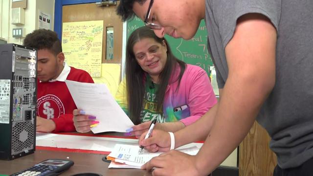 Teacher Billy Green sits at a table with two students. 