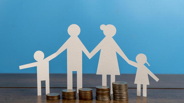 Family paper-cut figure model with money coin on the table. 