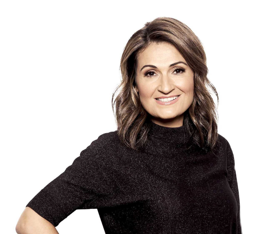 An olive-skinned woman with brown shoulder-length hair and a sparkly black top smiles.