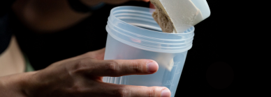 Guy putting protein powder into a shaker bottle after a workout.