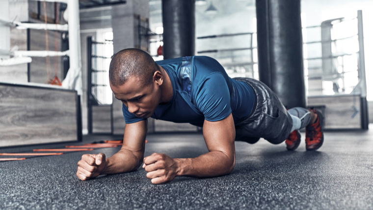 A person performs a forearm plank in the gym.