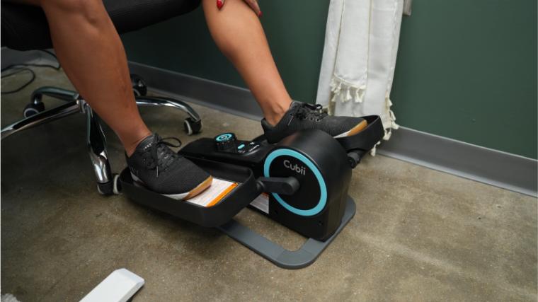 A person using the Cubii Move under-desk pedaler.