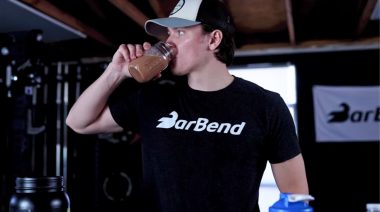 A person drinking a protein powder shake from a glass.