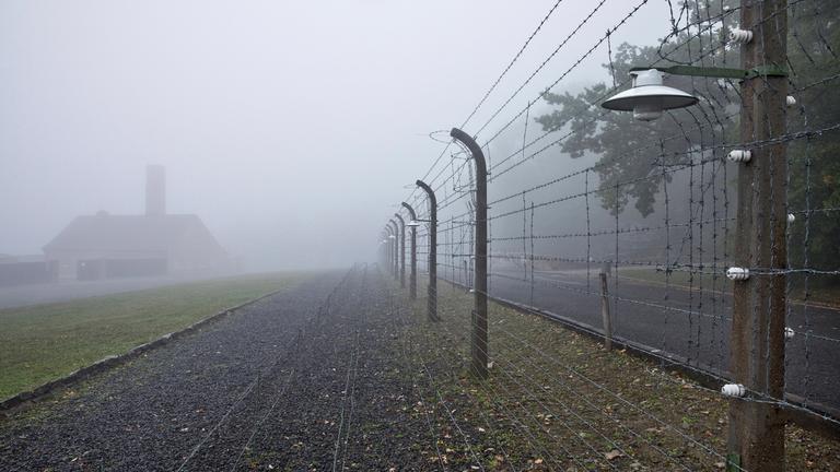 Rekonstruierter Lagerzaun mit Krematorium im Nebel in der Gedenkstätte des ehemaligen KZ Buchenwald.