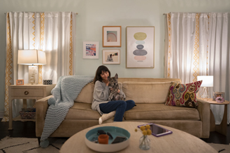 Woman sitting on a couch in her apartment with a puppy on her lap