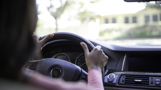 Inside view of a woman steering a car.