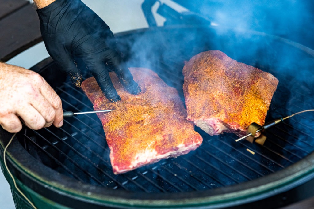 PRobing the ribs between the bones on the smoker