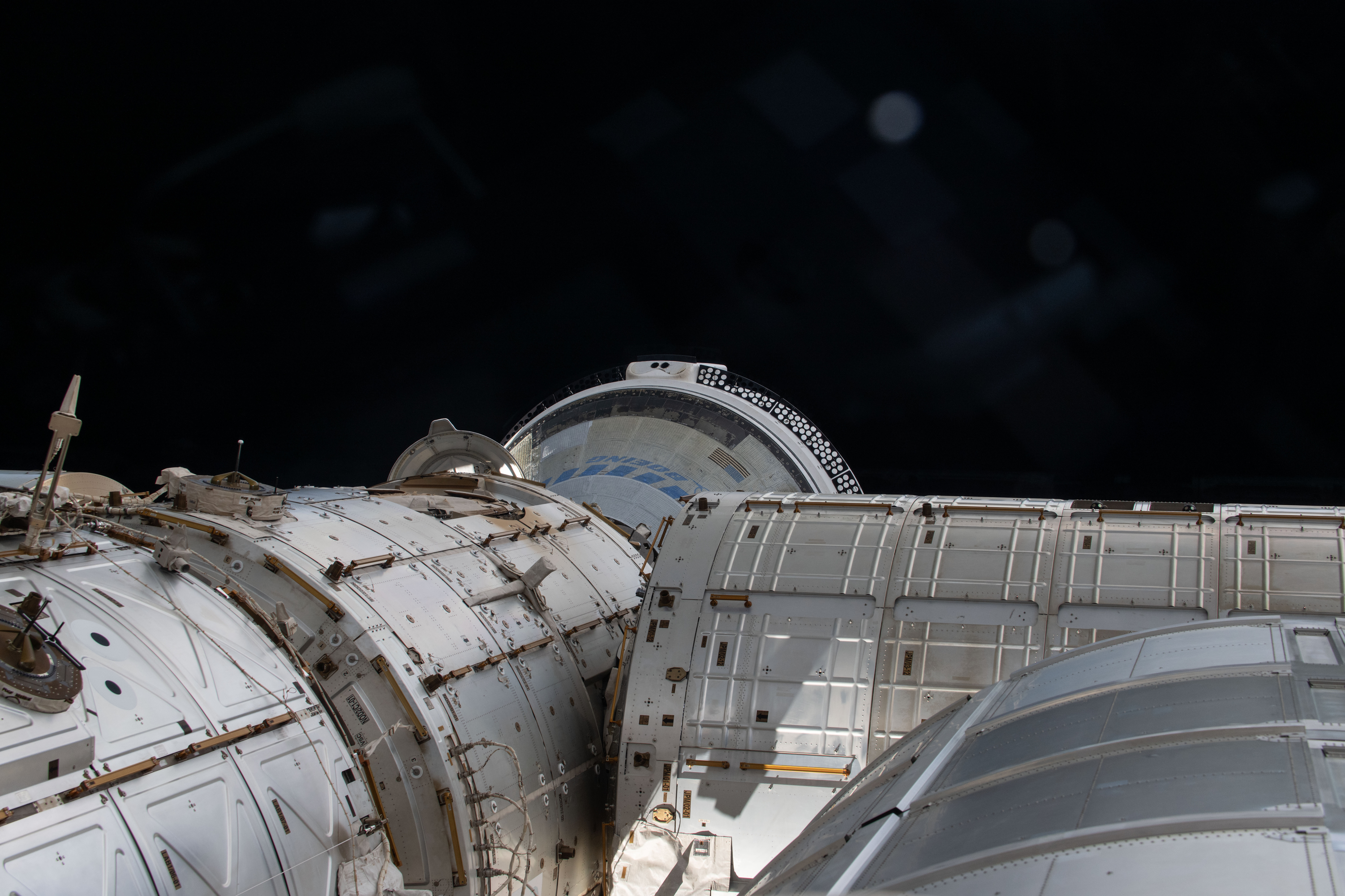 This view from a window on the cupola overlooks a portion of the International Space and shows the partially obscured Starliner spacecraft from Boeing docked to the Harmony module's forward port.