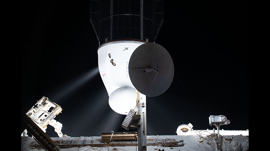 Plumes are pictured from the SpaceX Cargo Dragon's Draco engines as they fire following the undocking from the space station's Harmony module's space-facing port.