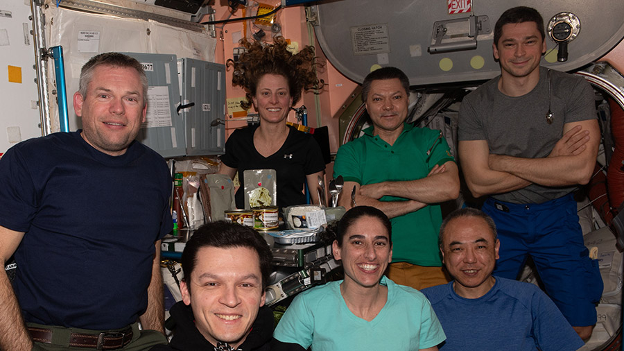 The seven-member Expedition 70 crew gathers for a dinner time portrait inside the International Space Station's Unity module.
