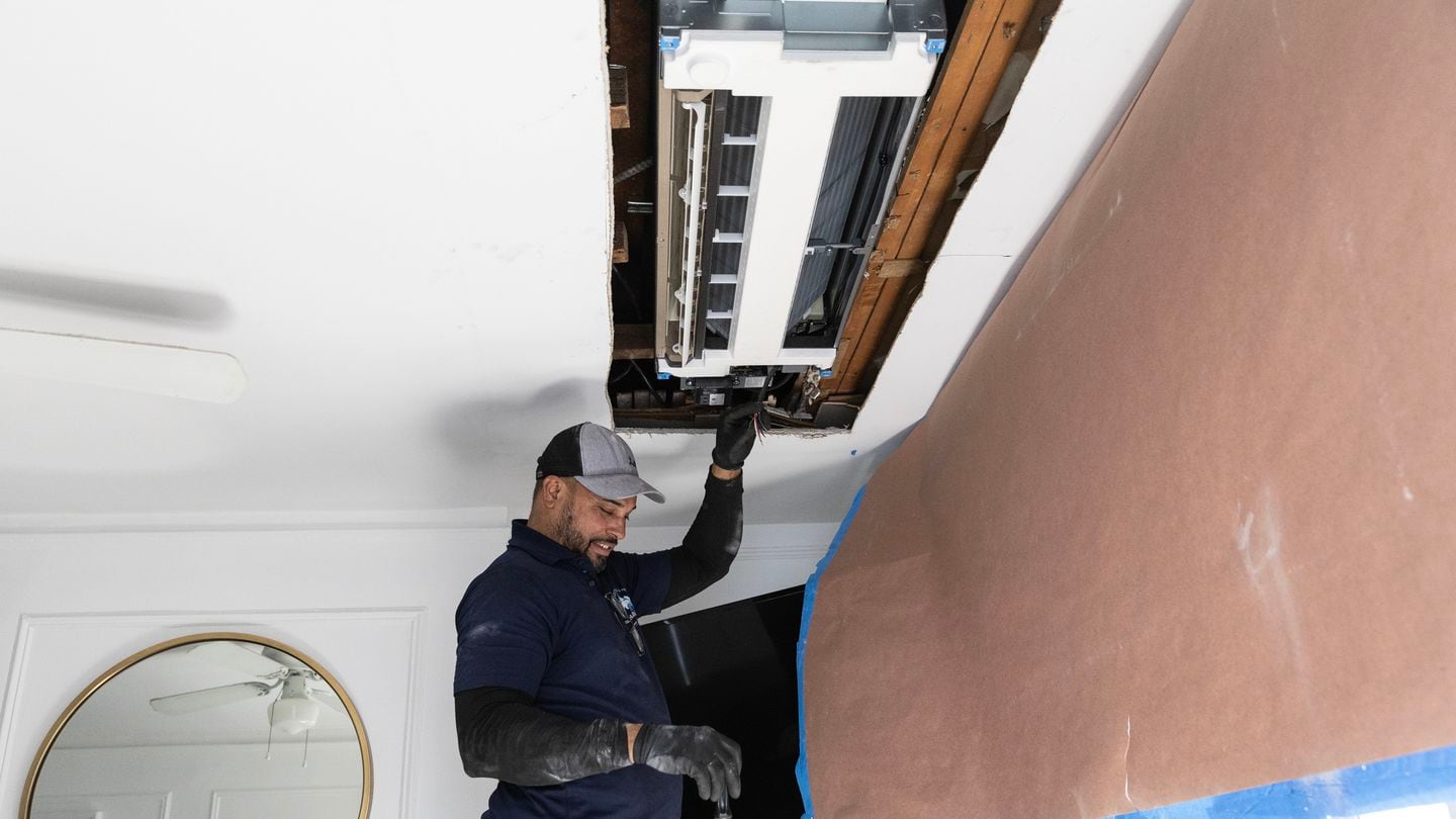 Victoriano Mosquea Rodriguez installs an indoor ceiling cassette unit, part of a heat pump climate control system, in Brooklyn on April 9, 2024.