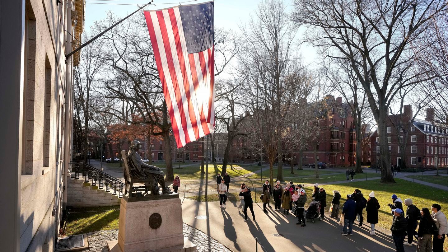 People take photos near a John Harvard statue on the Harvard campus in January.