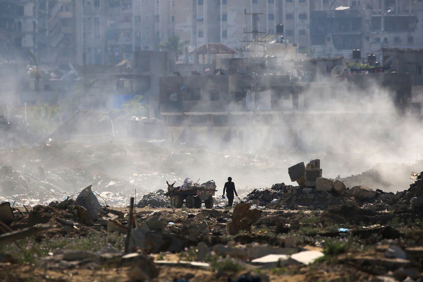 A Palestinian man salvaged items from a waste dump atop building rubble at al-Bureij camp in the central Gaza Strip on June 2. 