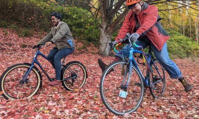 Two riders glide over a carpet of bright red leaves.