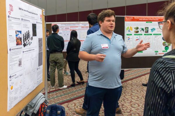 a man tells passersby about his research poster