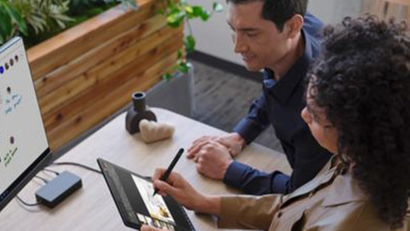 Personne écrivant sur une Surface Go 3 avec une autre personne qui regarde