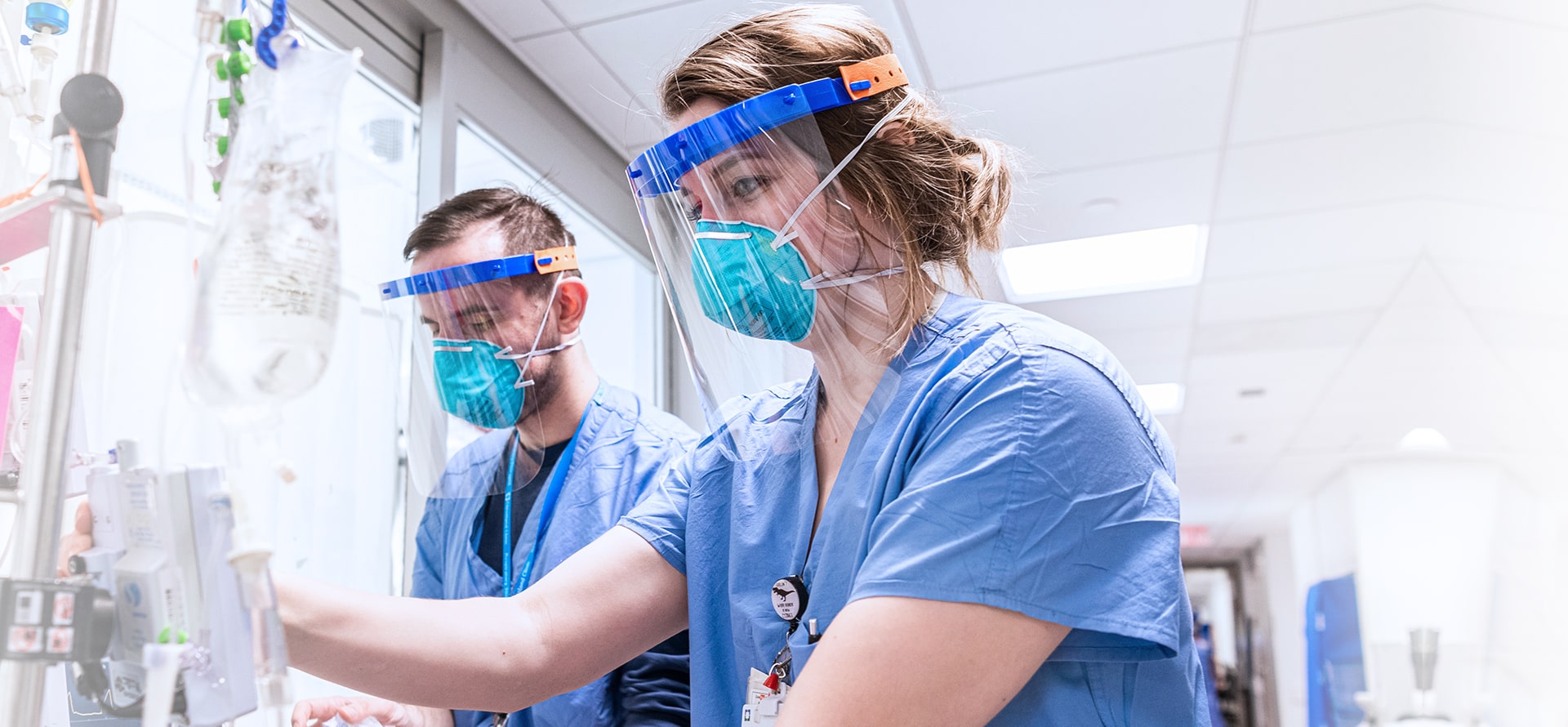 masked and shielded medical professionals focusing on medical equipment