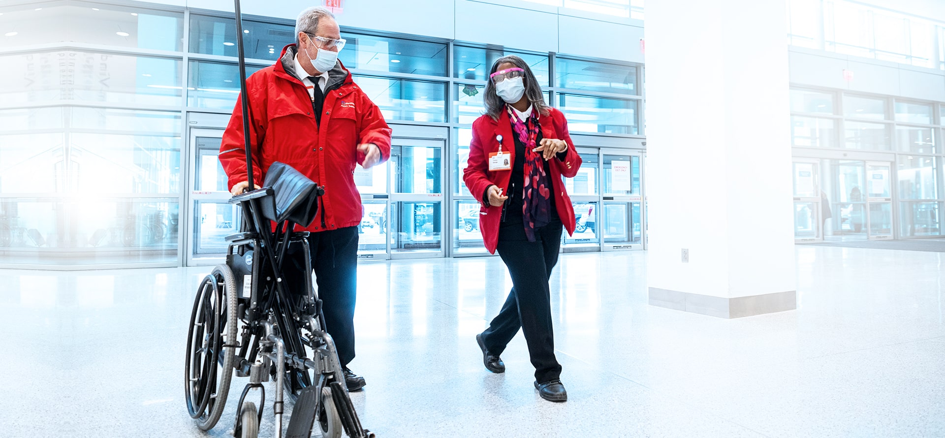 2 masked customer service representatives talking at a hospital entrance