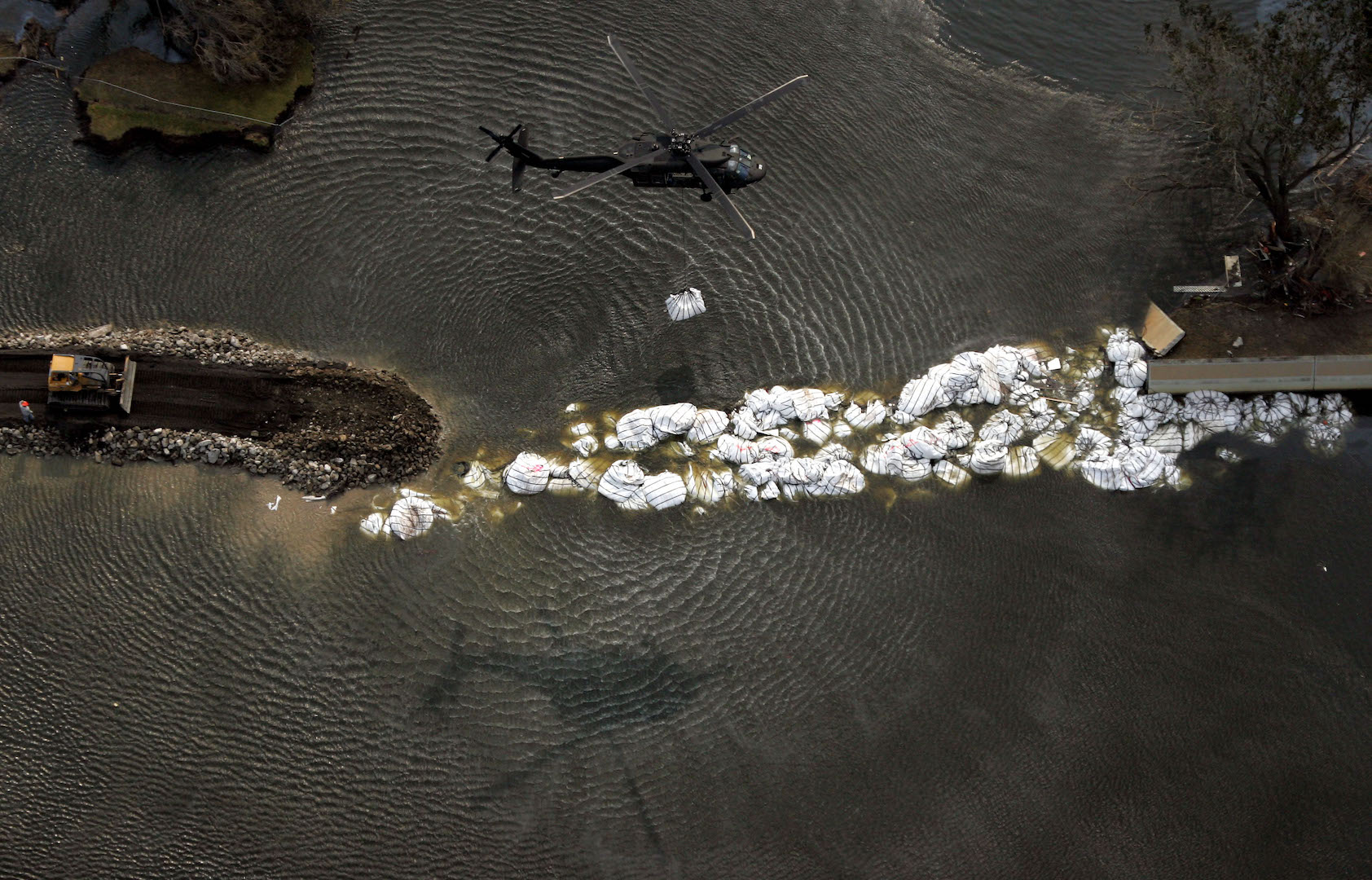 A military helicopter drops a sandbag as work continues to repair the 17th Street canal levee Monday, Sept. 5, 2005, in New Orleans.