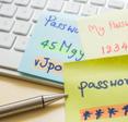 A set of three sticky notes lie on top of a computer keyboard with several passwords written on them