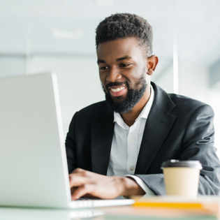 A man types on his laptop while at the office. 