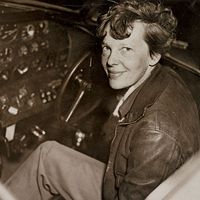 Amelia Earhart sitting in the cockpit of an Electra airplane.