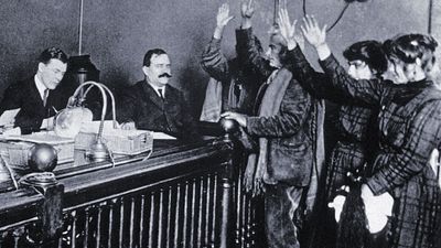 Black and white photo of people in courtroom, hands raised, pledging